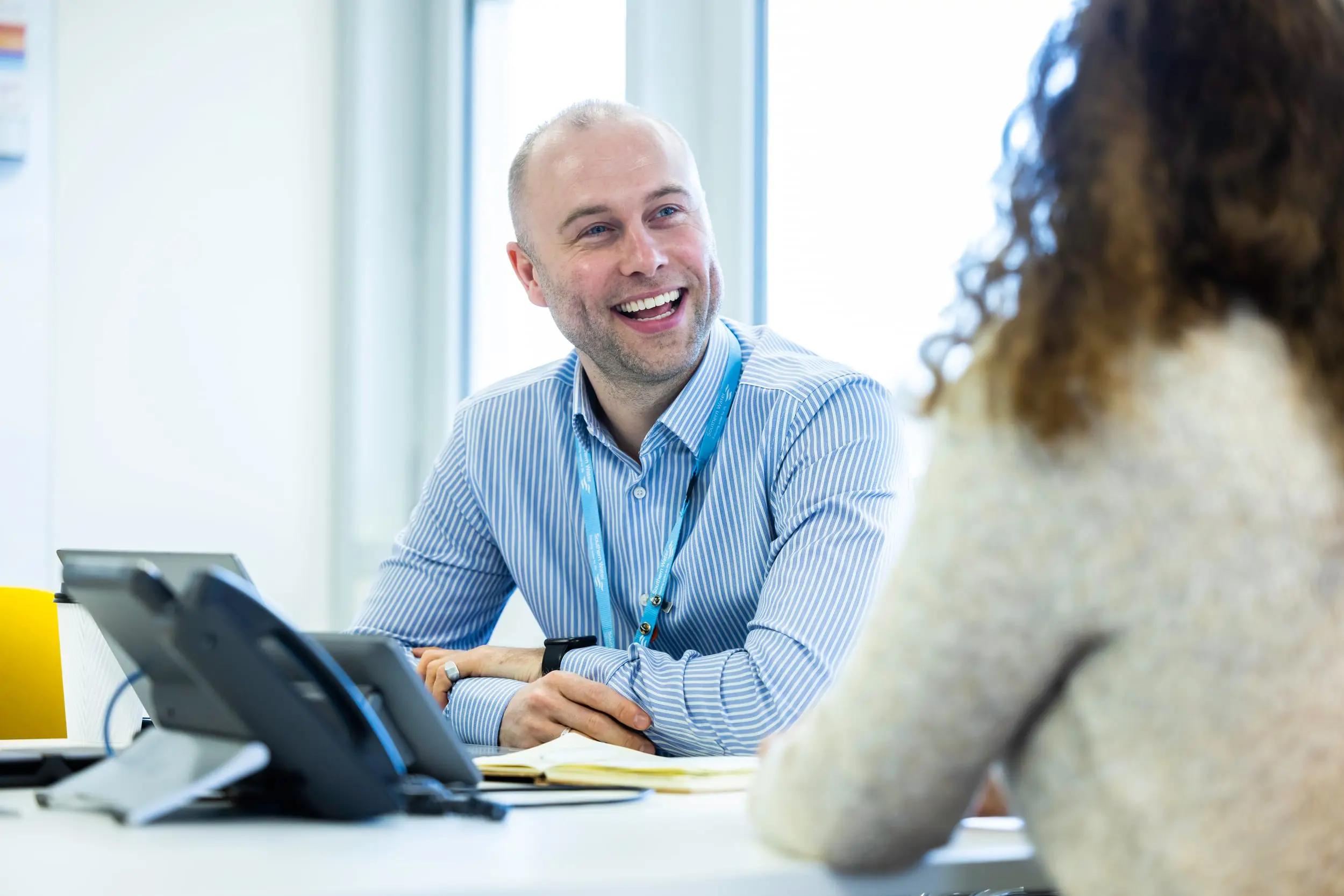 Smiling man talking to a colleague at work